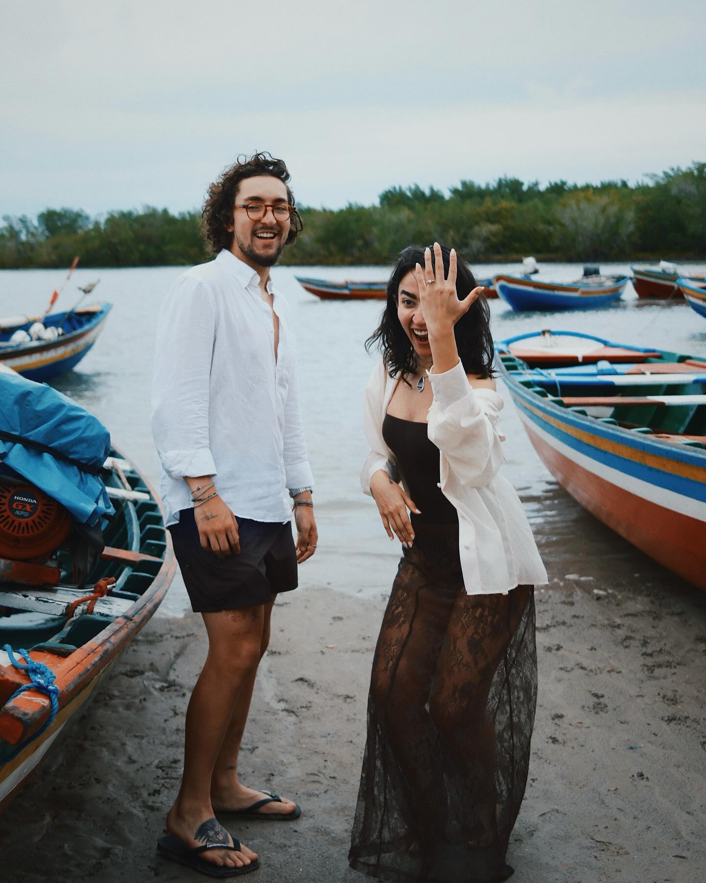 Giulia mostra o anel ao lado de Gui, com barcos ao fundo